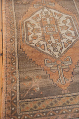 Distressed Oushak rug showing geometric patterns, faded terracotta, and visible wear.