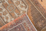 Distressed vintage Oushak rug close-up, revealing geometric motifs in faded rust and sand.