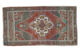 Distressed vintage Oushak rug, a scalloped floral medallion in chestnut, ivory, and muted green.