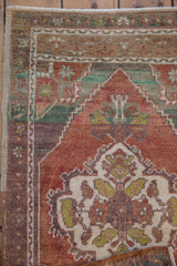 Close-up of distressed Oushak rug showing scalloped medallion and finned floral blossoms.
