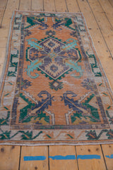 Vintage Distressed Oushak rug runner corner, showing teal scrolling serrated leaves, primitive border, and wear.