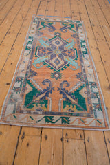 Distressed Oushak runner close-up, central blue medallion, finned floral blossoms, and worn orange field.