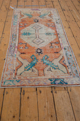 Distressed vintage Oushak runner's tangerine orange field and turquoise mint green scrolling leaves.