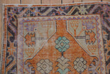 Vintage Oushak rug corner detail, highlighting distressed tangerine, brown, and violet border with mint green bud.
