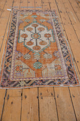 Distressed Oushak rug corner with worn tangerine, ivory pile and meandering border pattern.