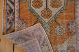 Corner view of vintage Oushak rug, showing distressed pale tangerine pile, mint accent, and lavender reverse.