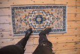 Distressed hand-knotted Turkish Oushak rug with stepped medallion and beige, indigo, sand tones.