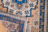 Distressed Oushak rug's worn pile, indigo border, and geometric beige motifs.