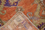 Distressed Oushak rug pile with burnt orange and violet, revealing its tightly woven foundation and fringe.