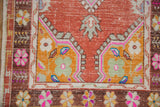 Distressed vintage Oushak runner corner showing saffron gold spandrel, dusty blush field, floral motifs.