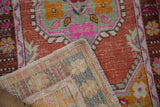 Folded corner of vintage Oushak rug, showing distressed pile with faint foundation and hand-knotted reverse.