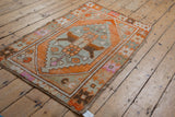 Distressed Oushak rug corner showcasing tangerine orange, oxidized silver geometric patterns.