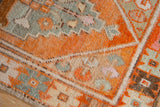 Distressed tangerine orange, sage green geometric motifs, and stepped contours on a vintage Oushak rug.