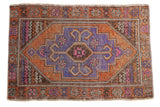 Vintage distressed Oushak rug with geometric lavender medallion, ram's horn motifs, burnt orange field.