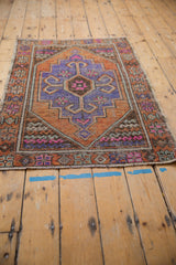 Distressed vintage Oushak rug detail featuring geometric medallion, ram's horn, in purple and orange.