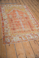 Distressed Oushak rug corner with dusty red and saffron geometric border, even pile wear.