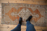 Distressed terracotta Oushak runner, ivory stepped medallion with splayed floral motifs.