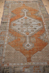 Distressed pile of the Oushak runner, showing terracotta, ivory, and charcoal geometric motifs.