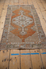 Distressed Oushak rug corner with terracotta field, oxidized silver lattice spandrel, fringed edge.