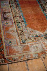 Distressed Oushak rug with abrashed terracotta field, foundation showing through, and floral borders.