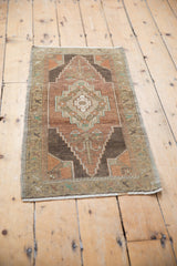 Distressed Oushak rug with stepped medallion, floral laurel motif, and muted tones.