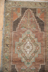 Distressed Oushak rug detail showing stepped medallion, floral motif, and abrashed aubergine field.