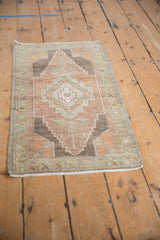 Distressed vintage Oushak rug mat featuring stepped medallion in aubergine and ivory.
