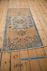 Distressed vintage Oushak rug corner, showing blue ribboned cloud band motif and fringe.