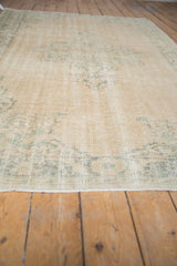 Vintage distressed Oushak rug pile showing wear, ivory, and faded green motifs.