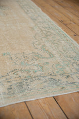 Textured worn pile of a vintage Oushak carpet, showing faded seafoam green border.