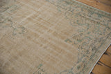 Textured wear and faded green border on a distressed vintage Oushak rug corner, with intact selvage.