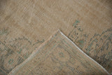 Distressed vintage Oushak rug showing its hand-knotted foundation and intact corded selvage.