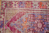 Distressed Oushak rug's coarse pile, fuchsia, aubergine, green motifs, foundation showing.