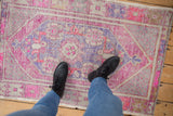 Distressed vintage Oushak rug in vibrant pink, purple, and gray underfoot.
