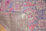 Distressed Oushak rug folded, showing blush pink, aubergine pile with wear, and woven foundation.