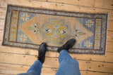 Worn texture and muted colors of a distressed Oushak rug's geometric pattern.