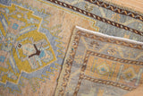Gold, blue, and beige distressed pile with intact secured side selvage of a vintage Oushak rug.