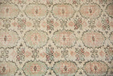 Distressed vintage Oushak rug, repeating gul pattern in soft ivory, seafoam, and blush tones.