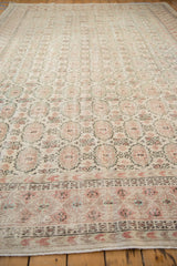 Distressed Oushak carpet featuring pale blush and seafoam gul motifs with textured wear.