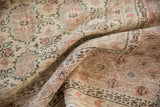 Distressed texture of a vintage Oushak carpet with faded ivory, blush, and seafoam gul motifs.