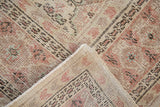 Distressed vintage Oushak pile showing ivory, blush, and seafoam gul motifs with intact selvage.