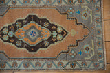 Distressed Oushak rug corner showing sandalwood field, slate blue spandrel, and patterned border.
