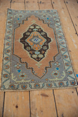 Oushak rug corner with muted sandalwood field, pale slate blue spandrel, and worn border motifs.