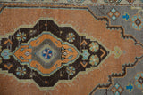 Distressed Oushak rug detail showing corner spandrel, sandalwood, and faded blue with wear.
