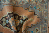 Folded detail of vintage distressed Oushak rug showing sandalwood and slate blue motifs.