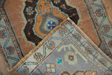 Distressed Oushak rug corner, showing sandalwood and blue pile with visible hand-knotted foundation.