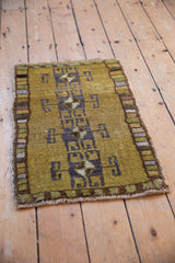 Distressed Kars rug, dusty gold green field, geometric ram's horn pattern, and multi-colored border.