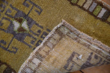 Distressed vintage Kars rug showing even pile wear, geometric dusty gold green, and woven back.