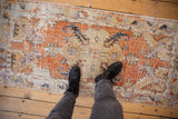 Distressed vintage Oushak runner, worn floral medallion, terracotta, seafoam, and ivory tones.