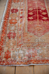 Distressed Oushak rug runner border detail with rhythmic red, blush, and beige geometric and ribboned motifs.
